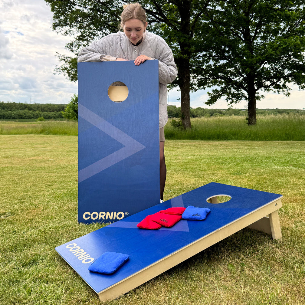 Cornio cornholegame with blue printed UV print outside in the grass summer with cornholebags